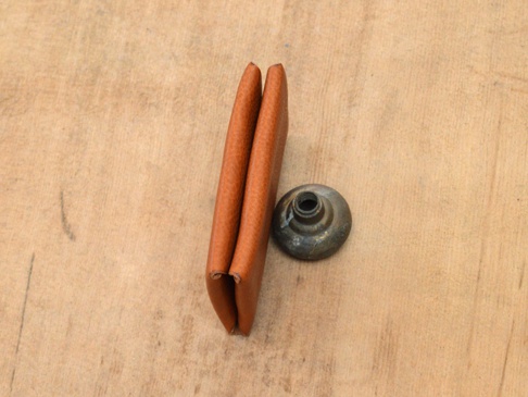 棕色皮革製成的雙開卡片收納夾，緊閉著，旁邊有一個金屬鈕扣。