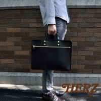 黑色皮革兩用公事包，配有金色拉鍊和铆釘。