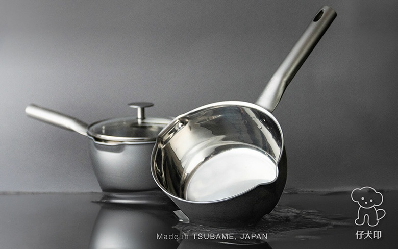 兩個不鏽鋼雪平鍋，一個有玻璃鍋蓋，另一個是單柄的，鍋身呈現銀色金屬光澤，底部有水漬。