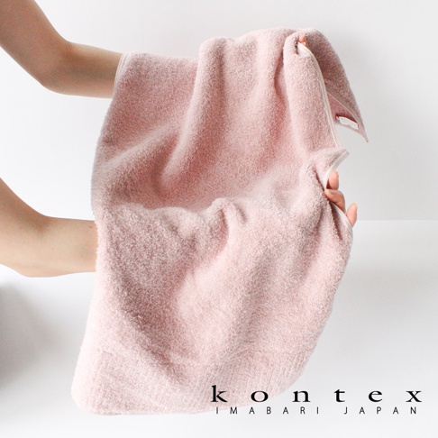 雙手捧著粉色極柔蓬鬆大毛巾，展現其柔軟質感與蓬鬆外觀。