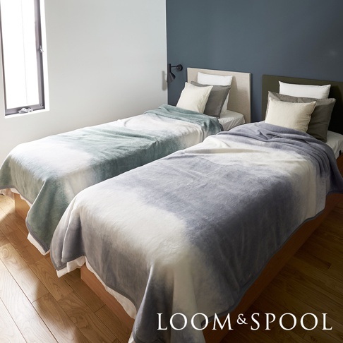 兩張單人床分別覆蓋著淺綠色與灰色漸層的短絨舒柔單人毯，毯子觸感輕柔，呈現自然的暈染效果。