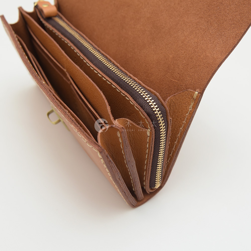 駝色皮革手風琴式長夾，內部有多個卡片夾層和拉鍊袋，手工縫線，附有金屬扣環。