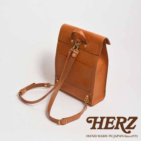 職人手作皮革紙袋風後背包，採用光滑的棕褐色皮革製成，配有可拆卸的肩帶和金色金屬配件。