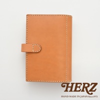 職人手作淺棕色皮革記事本書套，圓形皮革鈕扣開合，車縫線明顯，簡約設計。