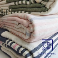 堆疊的六層紗條紋毛毯，有綠色、粉紅色和深藍色條紋，材質呈現細緻紋理