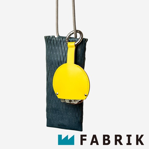 FABRIK 品牌綠色皮革編織手機套，搭配黃色皮革圓形鑰匙包，鑰匙包上有鑰匙和金屬環。