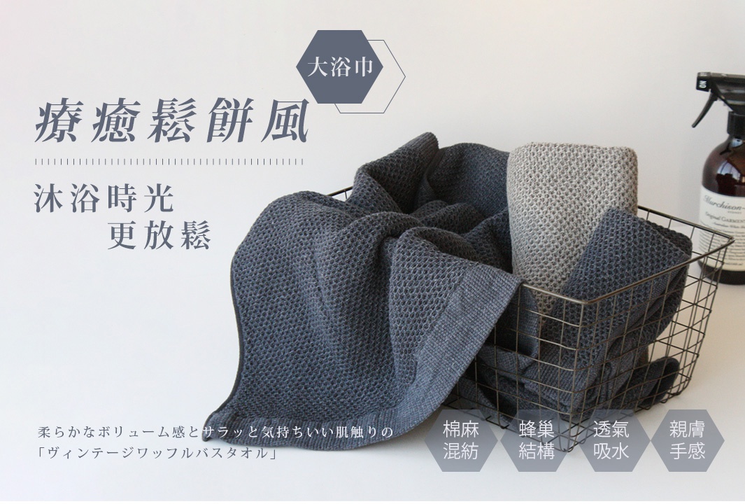 深灰色與淺灰色鬆餅紋棉麻混紡大浴巾，質感柔軟，收納於金屬籃中。