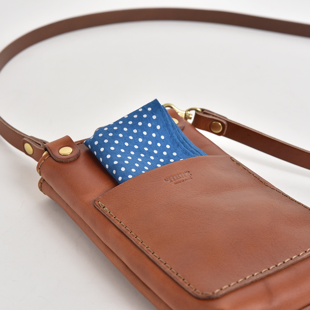 職人手作皮革兩用手機包，咖啡色皮革，包內裝有藍色圓點圖案的布料，附有可調整的棕色皮革背帶。