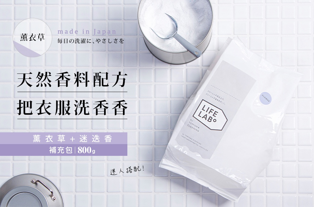 薰衣草口味洗衣粉補充包，白色塑膠包裝，印有「LIFE LAB」標誌及日文說明。背景為白色磁磚，畫面上方有一個裝有白色粉末及銀色勺子的金屬罐。