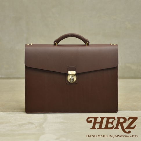 職人手作皮革Organ兩用商務公事包，深棕色，擁有經典的公事包造型，附有金色旋鎖和皮革提把，質感厚實。