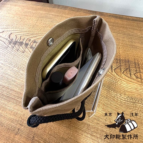 犬印鞄製作所的帆布手機包，內有手機、唇膏等小物，包包上有「東京 淺草 犬印鞄製作所」的標誌