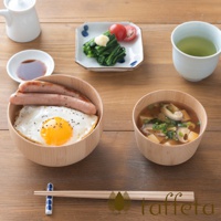 楓木碗裝有白飯、煎蛋和兩根香腸。右側的楓木碗裝有味噌湯，內有豆腐、香菇和蔥花。背景有醬油碟、裝有菠菜、番茄和蘿蔔泥的小盤，以及一杯綠茶。