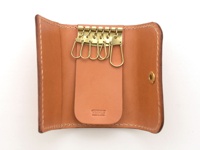 棕色皮革鑰匙包，內有六個金色金屬鑰匙鉤，中央皮革片上有壓印品牌標誌。