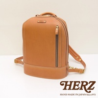 棕色皮革立體商務後背包，有拉鍊前袋和可調式背帶，整體線條簡潔，手工縫線清晰可見，是HERZ品牌出品。