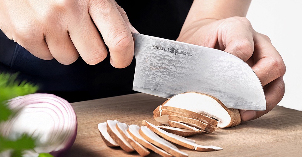 志津匠 都 Habahiro 多功能刀正在切片蘑菇，旁邊有一個切開的紅洋蔥