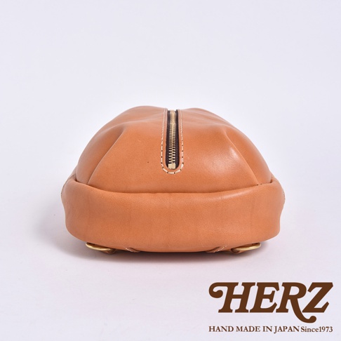 HERZ 品牌棕色皮革側背包，頂部有拉鍊設計，底部有金屬配件，標有「HERZ HAND MADE IN JAPAN Since1973」。