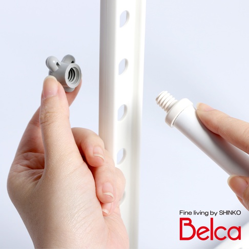 一隻手正將一個灰色、帶有兩個耳朵形狀突出物的組件，對準白色直立式收納架的孔洞。另一隻手則將一個白色管狀組件，其末端帶有螺紋，準備連接到收納架的另一個孔洞。