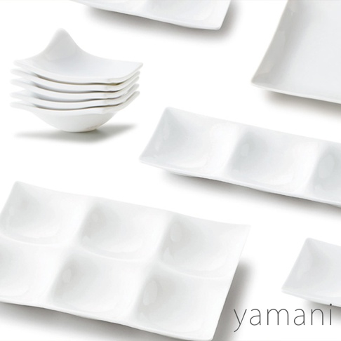 白色陶瓷九格小菜盤，盤面平整，格紋清晰，盤緣略帶弧度。另有堆疊的白色陶瓷小碟。