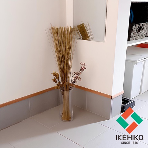 玻璃花瓶中裝有捆綁的天然藺草，呈現金黃色澤，旁邊點綴乾燥的小紅花和金色葉片，整體風格簡約自然。