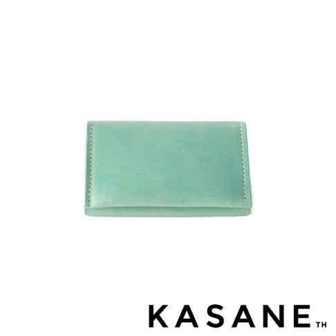 KASANE TH 品牌標誌旁是淺綠色皮革製成的卡片夾，帶有縫線細節。