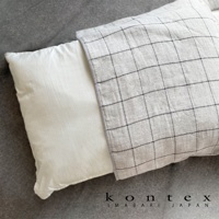 GRAPH 草木染格紋有機棉枕套，淺灰色織物表面帶有細緻的深灰色格紋，一側露出白色枕頭，材質為有機棉。