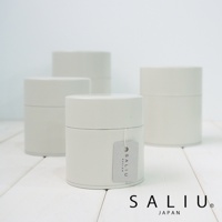 四個簡約設計的乳白色錫製圓形茶葉罐，其中一個罐子掛有灰色吊牌，印有「SALIU DESIGN」字樣。