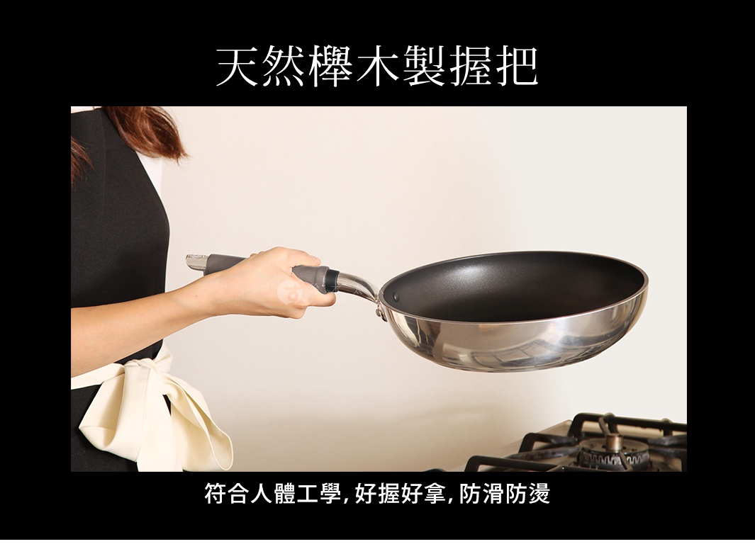 一只手正握著一個26公分的不鏽鋼平底鍋，鍋內為黑色不沾塗層，鍋柄為天然木製，鍋身下方是爐灶。