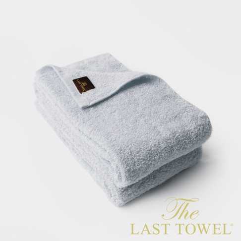 The LAST TOWEL 魔法瞬吸純棉柔長毛巾，兩條疊放，呈現淺藍色。毛巾質地柔軟，表面有細緻的絨毛，一條毛巾上繡有品牌標籤。