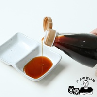 深褐色壽喜燒沾醬從透明塑膠瓶中傾倒至白色雙格陶瓷醬料碟中，醬料呈琥珀色，瓶蓋為米白色，有日文品牌標誌。