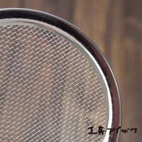 不鏽鋼萬用撈油勺的圓形網篩，網孔細密，邊緣為光滑金屬亮面。