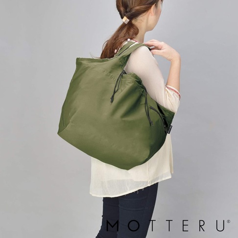 一位女性身背一個橄欖綠的大容量束口摺疊環保隨行袋，袋子為尼龍材質，兩側有束帶設計，可側肩背。
