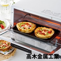 日本製烤箱用黑色波浪長形烤盤，內有兩個烤好的圓形派，派皮金黃酥脆，餡料包含番茄、青椒、火腿和融化的起司。