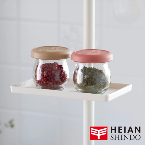 白色直撐架上的白色置物托盤，上面擺放著兩個透明玻璃罐，左罐裝有紅色顆粒，右罐裝有綠色乾燥葉片。兩個罐子都配有不同顏色的蓋子，左邊是棕色，右邊是粉紅色。