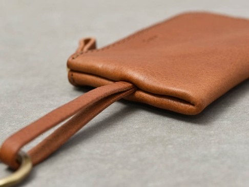 職人手作皮革Organ抽繩收納鑰匙包，採用柔軟的棕色皮革製成，配有金屬掛環和皮革抽繩。簡潔的設計，展現皮革的自然紋理。
