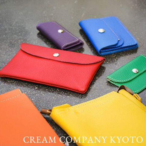多款顏色（紅、藍、綠、紫、黃、橘）的京都職人手作半月迷你手提包，採用帶有細緻紋理的皮革材質，每個包款都有一個金屬按扣和對比色的縫線。