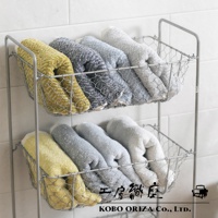 两层金属网篮中整齐叠放着 SUFFICE 棉麻混纺毛巾，毛巾颜色包括芥末黄、深灰、浅灰和浅蓝色，材质触感柔软蓬松。