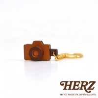 皮革製成的手機造型鑰匙圈，主體為棕色，鏡頭部分為深棕色。附有金色金屬鑰匙環。