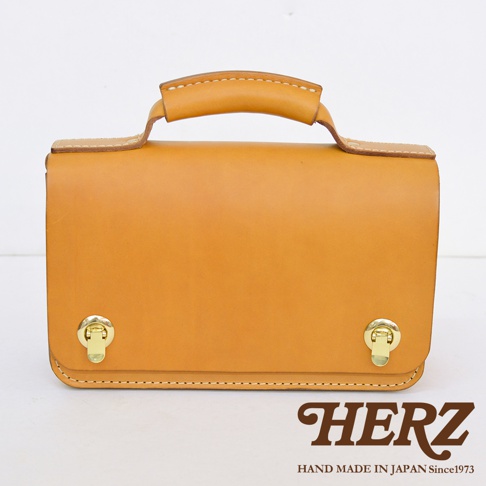 職人手作皮革經典兩用雙扣迷你單肩包，呈現自然色澤皮革，配有金色雙鎖扣及提把，簡約設計。