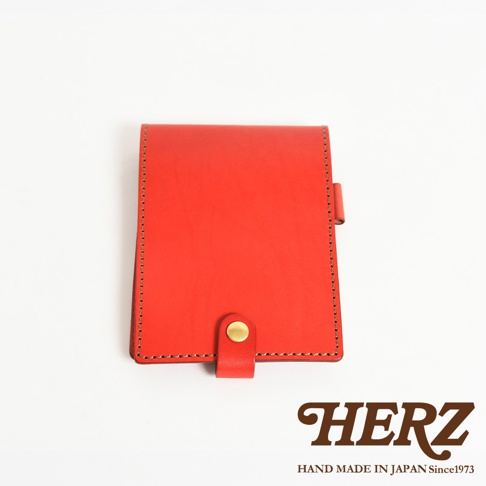 紅色皮革製成的便利貼收納套，附有金色按扣，邊緣有縫線裝飾。