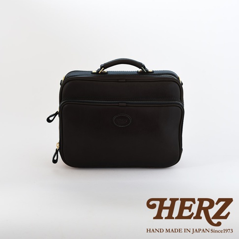 黑色皮革製成的手提公事包，有提把、拉鍊開合及品牌標誌。