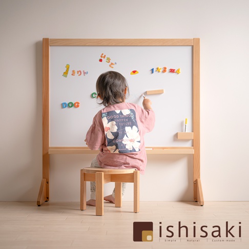 木藝兒童多功能繪畫白板，配有淺木色邊框，白色畫板上貼有彩色字母、數字及圖案磁貼，一名幼童坐在木製圓凳上，手持白色畫筆在白板上書寫。