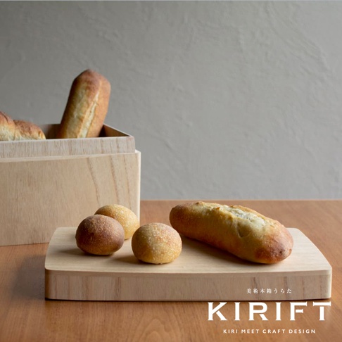 淺色木製麵包收納盒，盒內有數個法國麵包，前方木製砧板上擺放著三個圓形麵包和一條法國麵包，整體呈現溫暖質樸的風格。