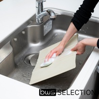 淺米色六片式摺疊隔板，表面有細緻的條紋，置於不鏽鋼水槽中，一隻手正用綠色海綿和泡沫清洗隔板。