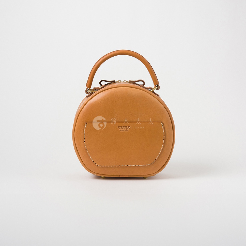 日本HERZ職人手作駝色皮革兩用圓形包，包身飾有品牌標誌及日文說明，搭配縫線細節與提把，簡約時尚。