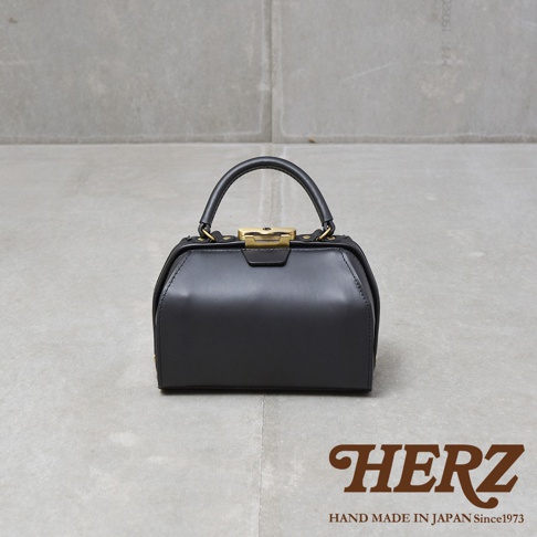 黑色皮革手提包，帶有金色口金開關和提把，展現簡約的方形設計。