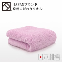 一條粉色加厚毛巾，材質柔軟，表面有絨毛感， folded 放置於白色背景上，左上方有品牌標誌及日文名稱「泉州こだわりタオル」，右下方有日文「日本桃雪」字樣。