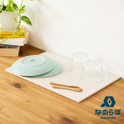 淺灰色斜面拼接珪藻土瞬間吸水置物墊，上面放置兩片淺藍色盤子、兩個透明玻璃杯及一雙木筷。