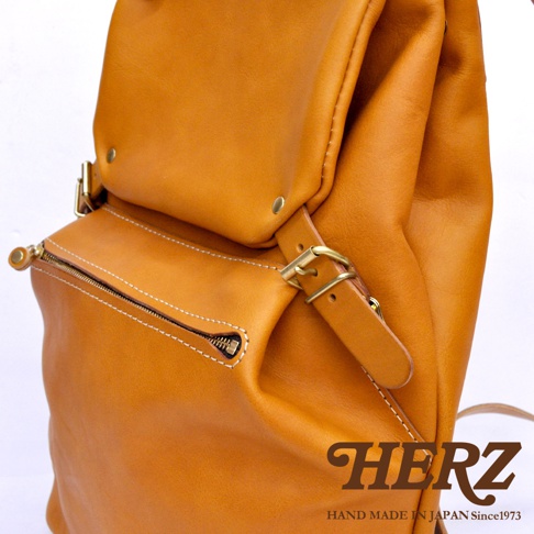 棕色皮革多口袋後背包，設有拉鍊前袋、翻蓋設計及金屬扣環，皮革質感厚實，縫線清晰，風格復古。