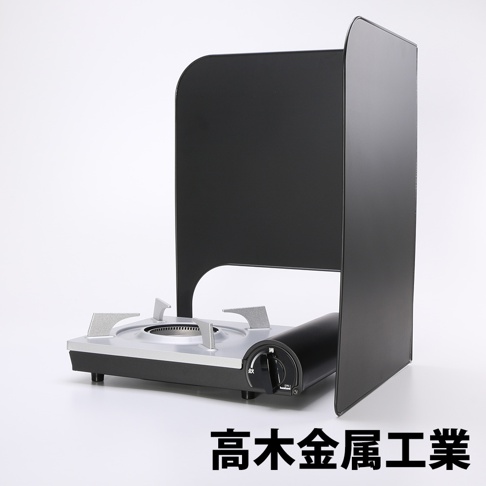 L型折疊擋油板，由金屬製成，呈現啞光黑色。擋油板呈L形，圍繞著一個銀灰色的便攜式瓦斯爐。爐體為黑色，設有黑色旋鈕。