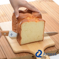 不鏽鋼麵包刀，刀刃帶鋸齒，木柄，正在切一塊金黃色外皮、內部柔軟的吐司麵包。